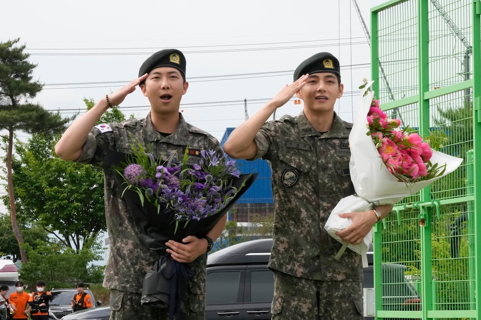 K-pop band BTS members RM, left, and V salute after being discharged from a mandatory military...